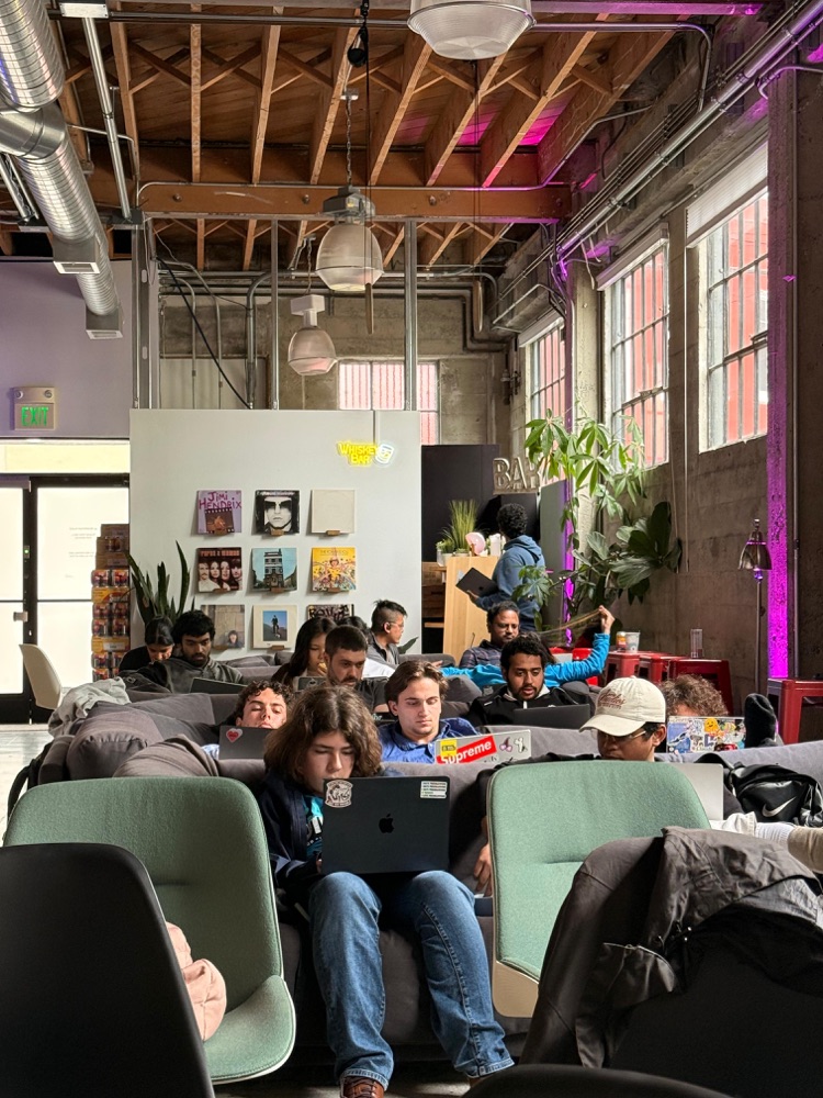 Hackathon participants coding on laptops in the lounge area